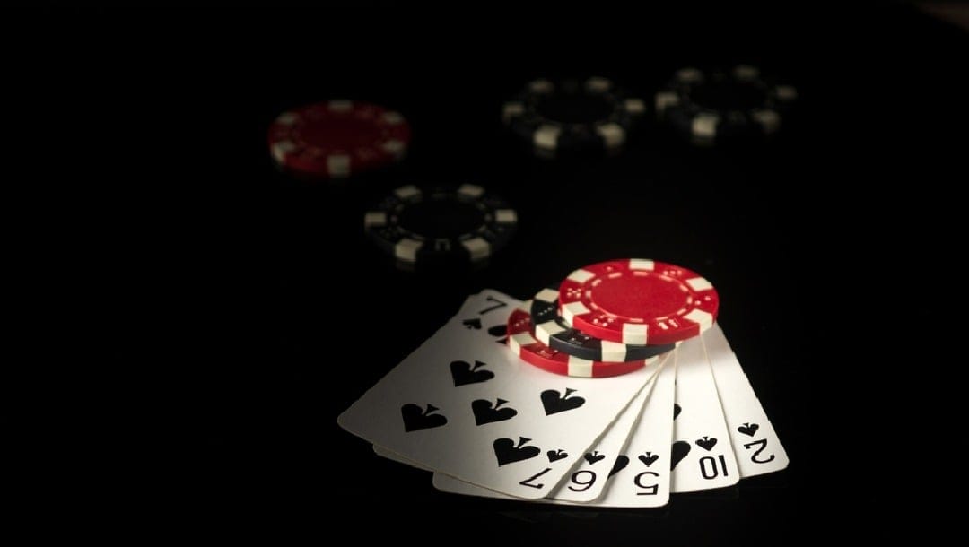 A flush of spades with chips on top of the cards.