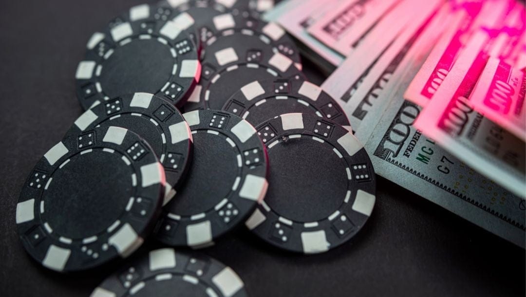 Black poker chips, and money on a table.