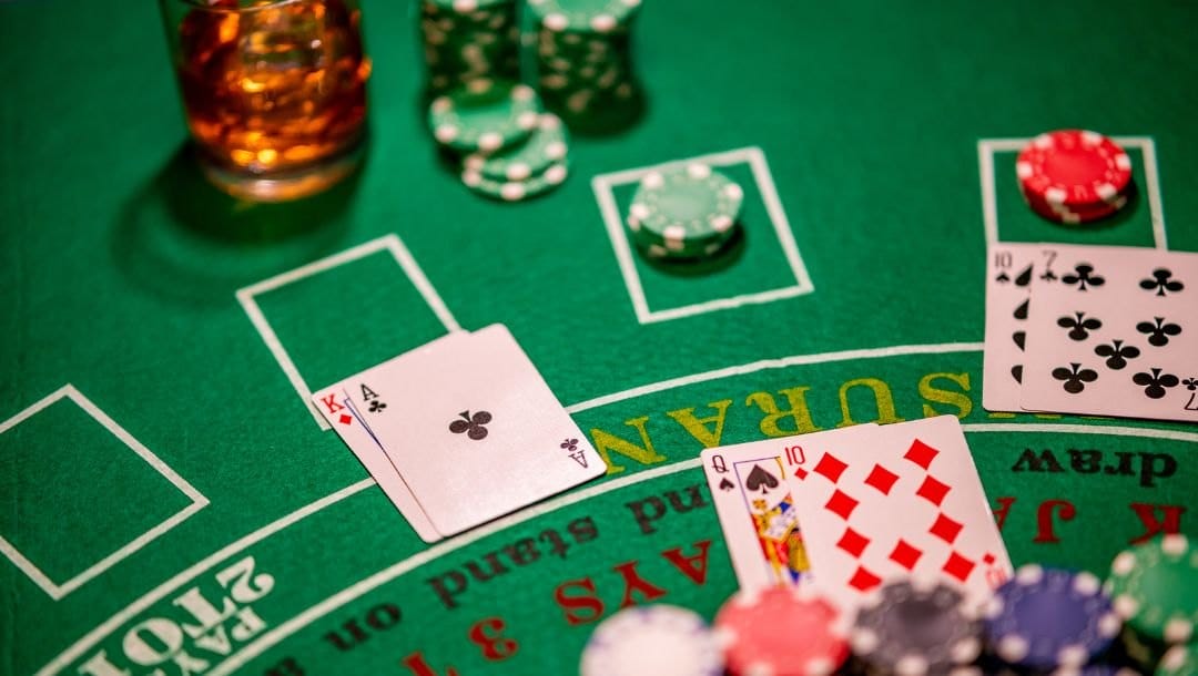 An view of a blackjack table, with casino chips, drinks, and playing cards on top of the table.