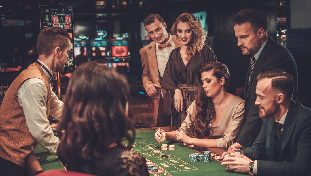 a group of people sitting around a roulette table in a casino