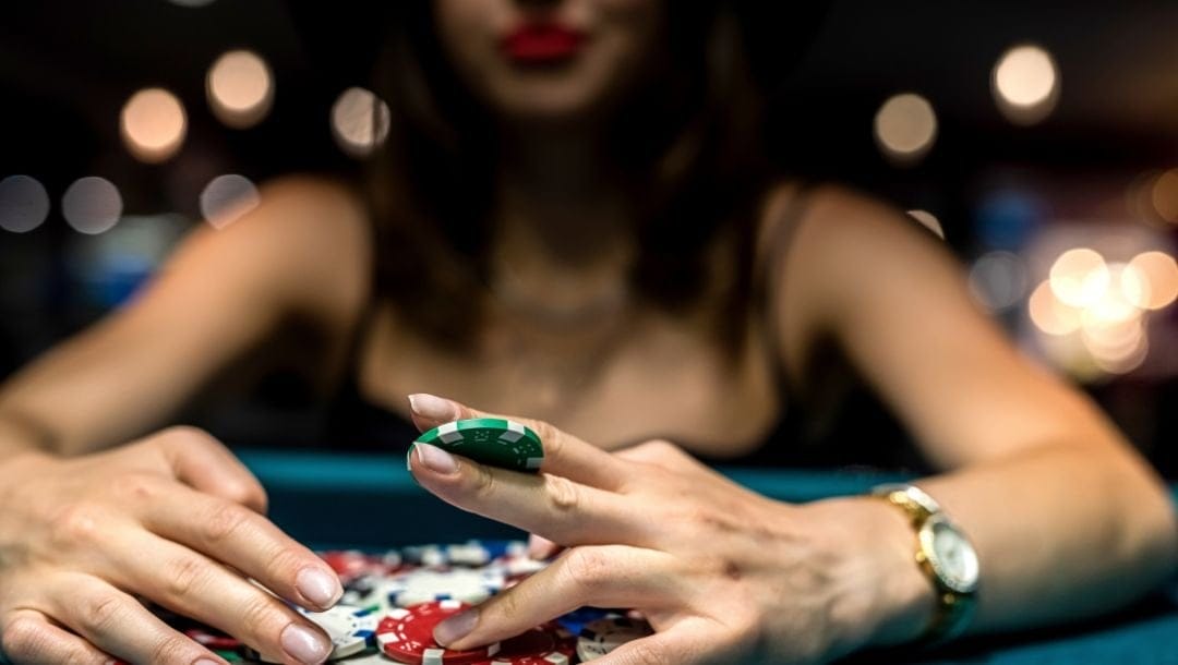 a woman is holding out a green poker chip over a poker table
