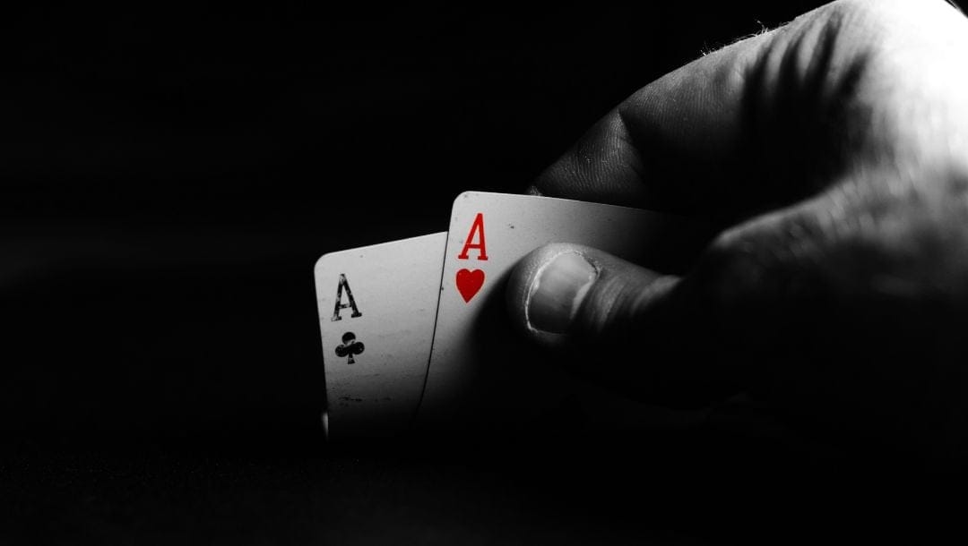 a close up of a person lifting a pair of ace playing cards
