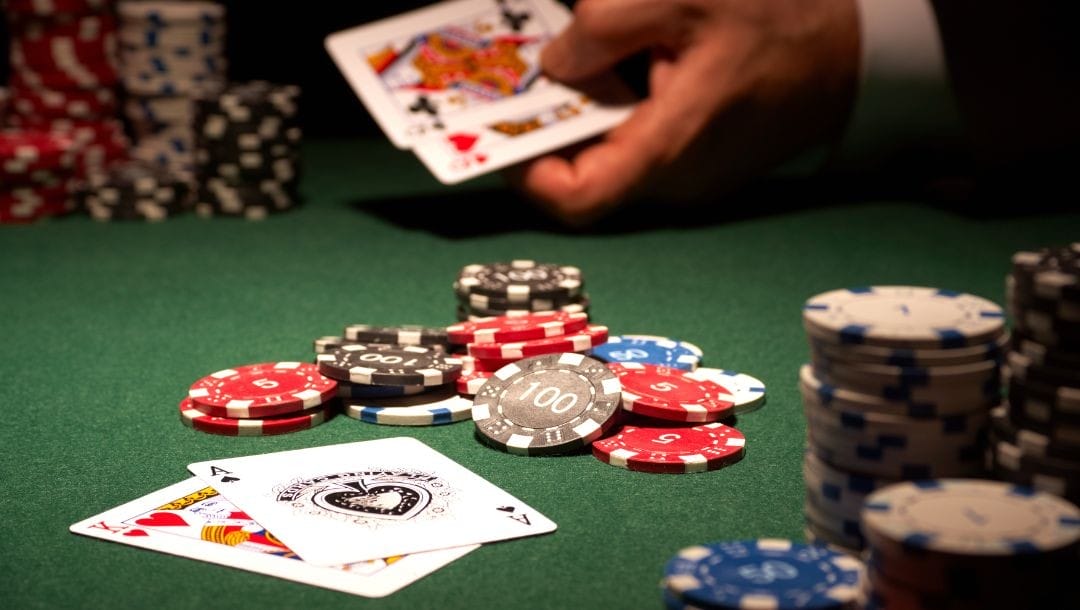 A photograph showing a winning poker hand on a green felt table, with a pile of poker chips in the center of the table and stacks of poker chips in the top right and bottom left corners.