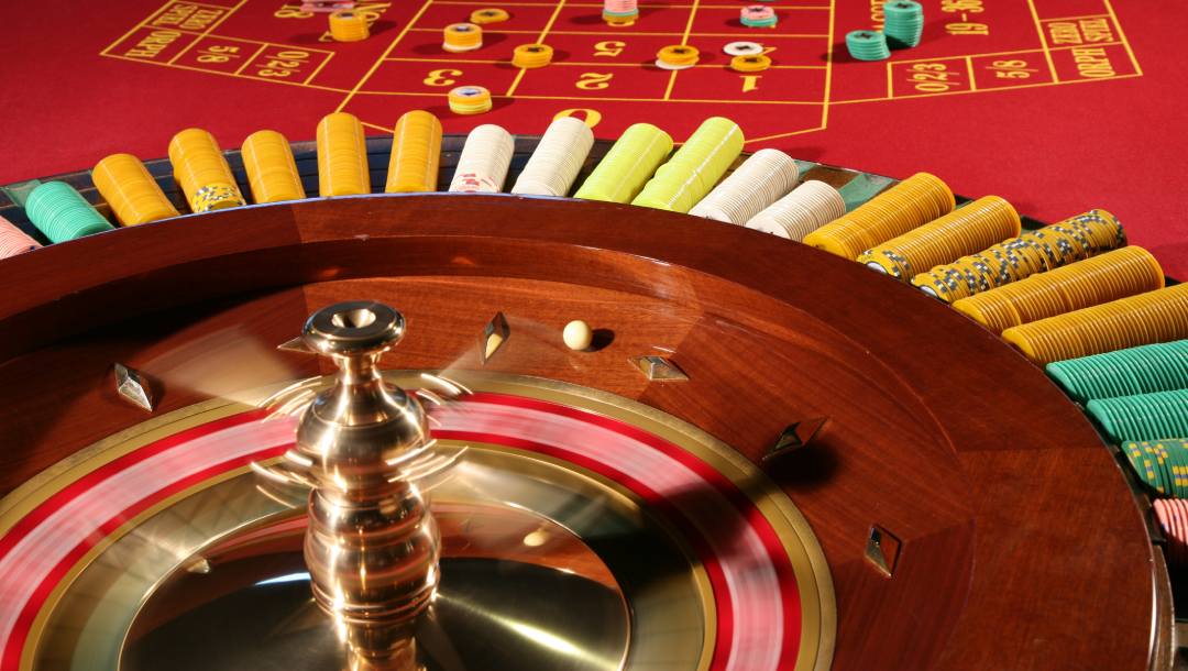 Old roulette table and wheel with casino chips.