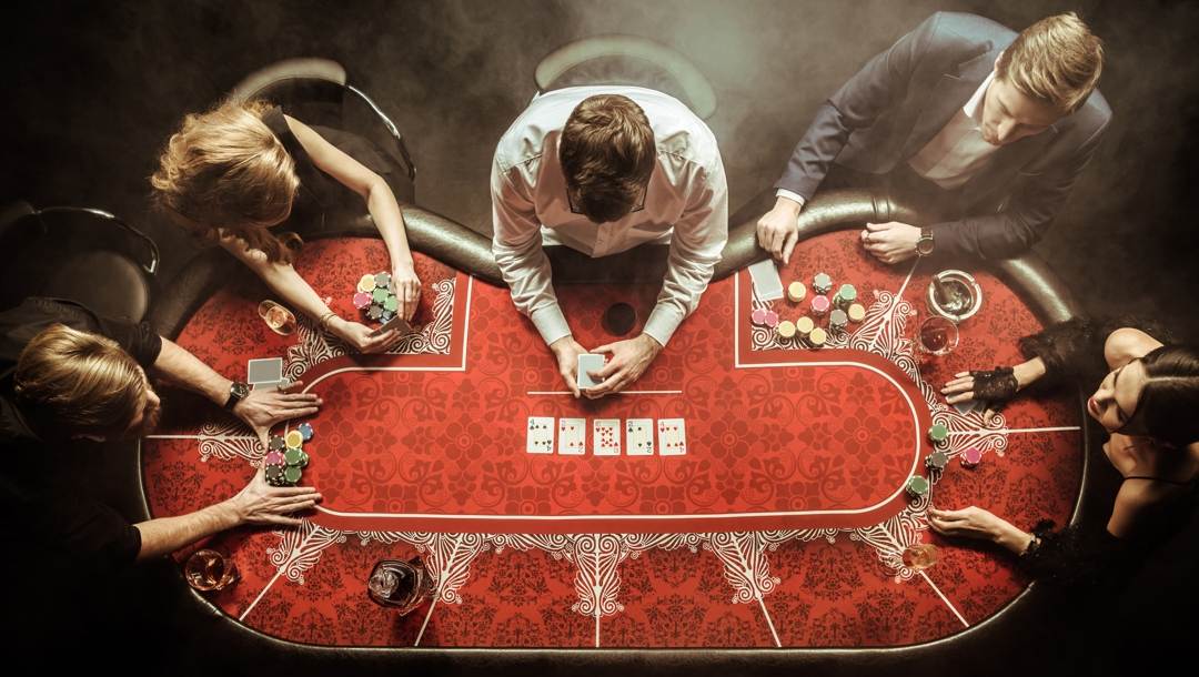 Bird’s eye view of players around a red poker table