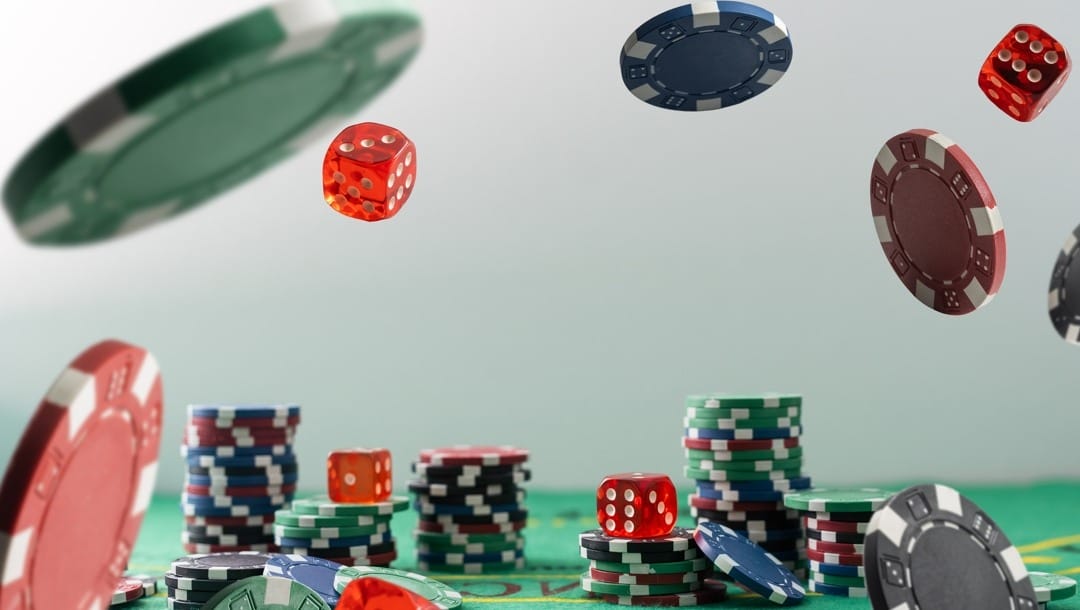 Poker chips and red dice tumbling from a height onto a poker table