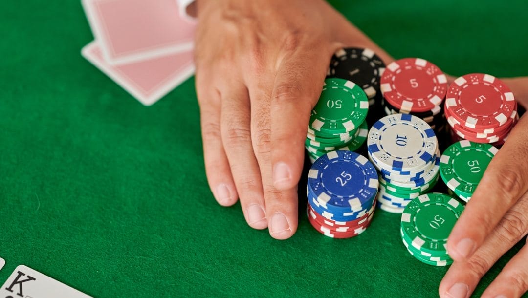 Hands pushing poker chips on a poker table