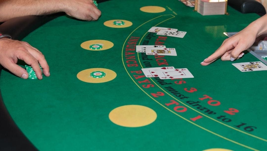 People sitting at a blackjack table, with playing cards and casino chips arranged on a table