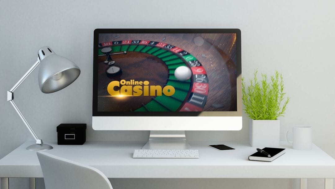 A computer on a desk, with an online casino game loading on the screen.