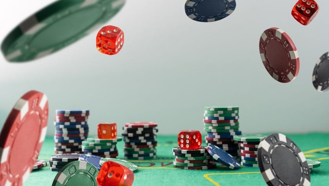 stacks of poker chips and red six-sided dice on a green felt poker table with poker chips and red six-sided dice falling in front of them