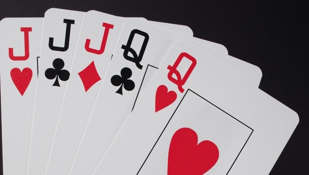 A closeup of three Jack playing cards and two Queens in different suits.
