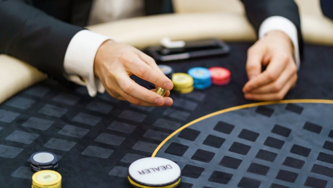 A poker player holding poker chips in his hand at the poker table.