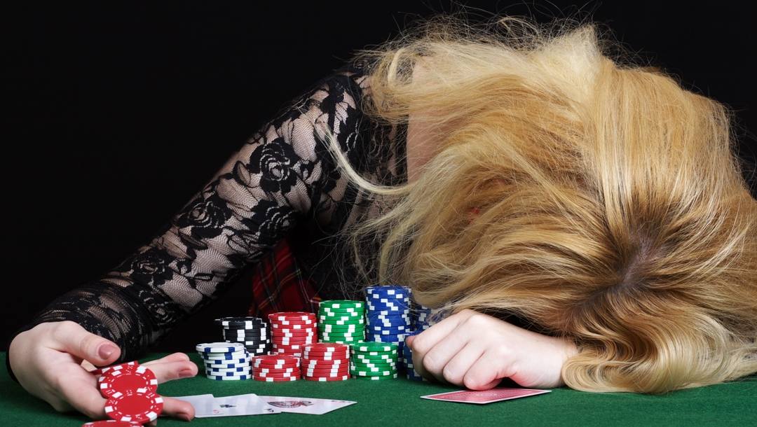 Blonde woman leans face-down on a green table after making a mistake in poker