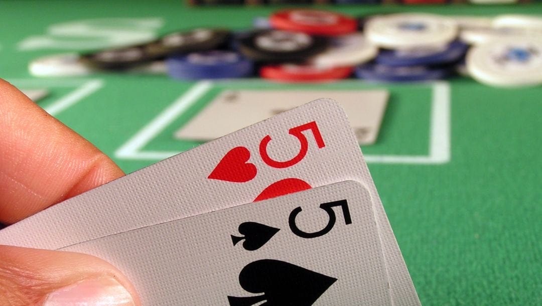 A pair of 5 playing cards featured against a casino table.