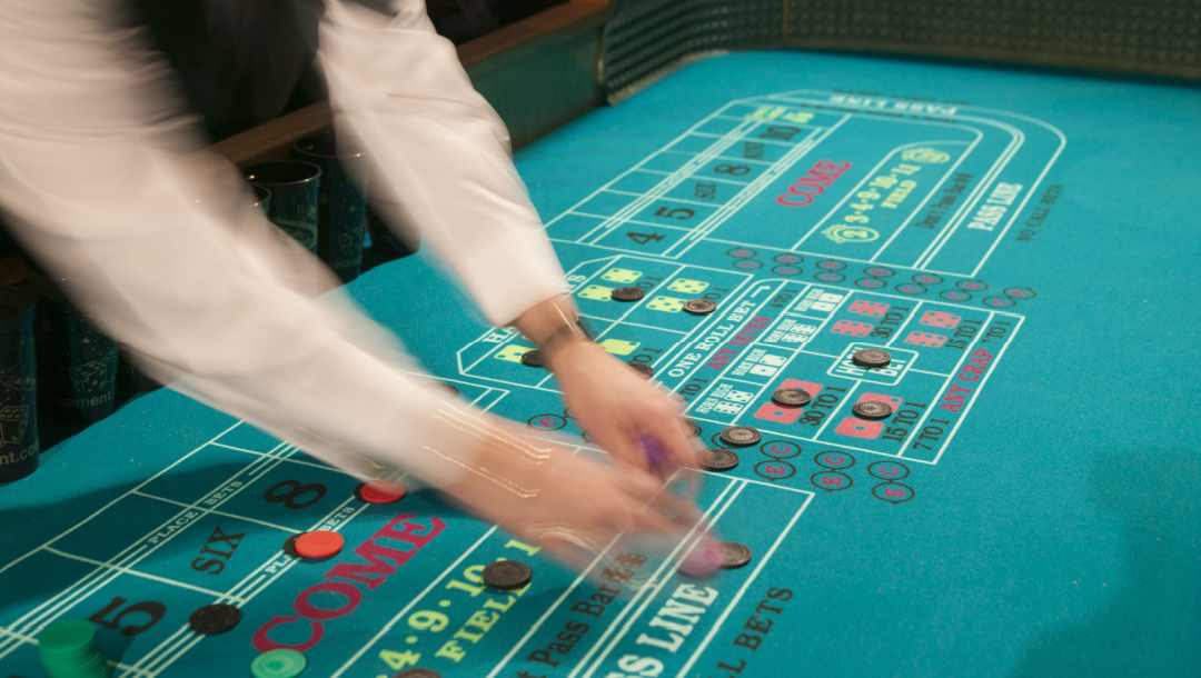 A blurred-out dealer at the craps table.