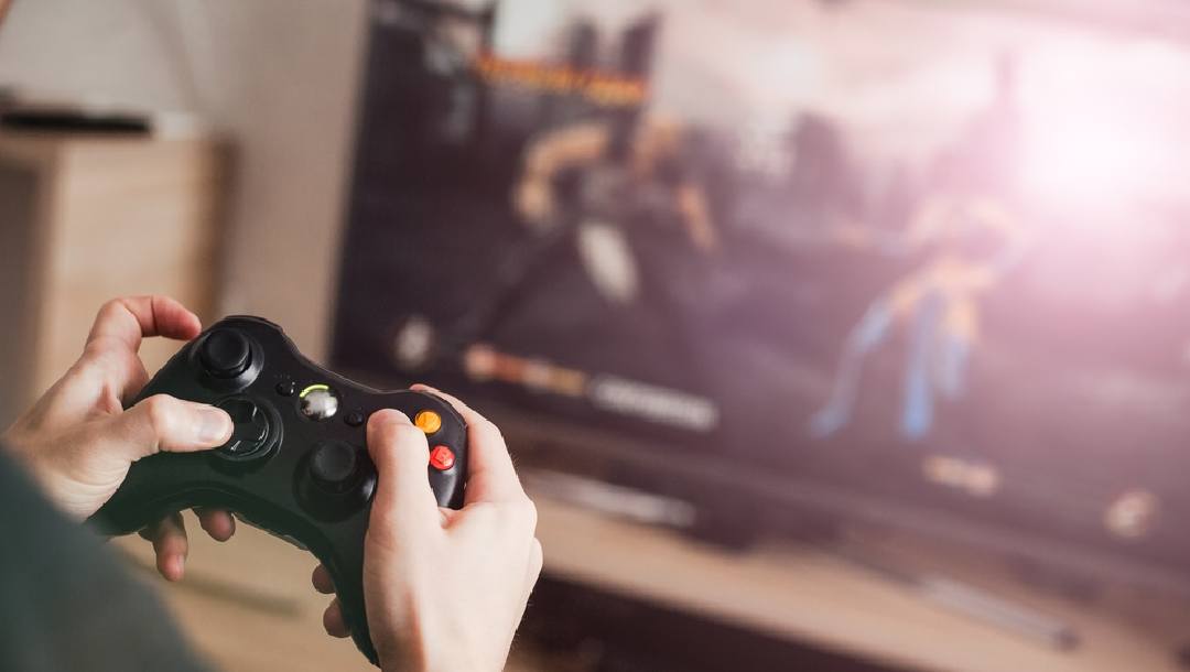 A close-up of a controller of a video game with a person holding it
