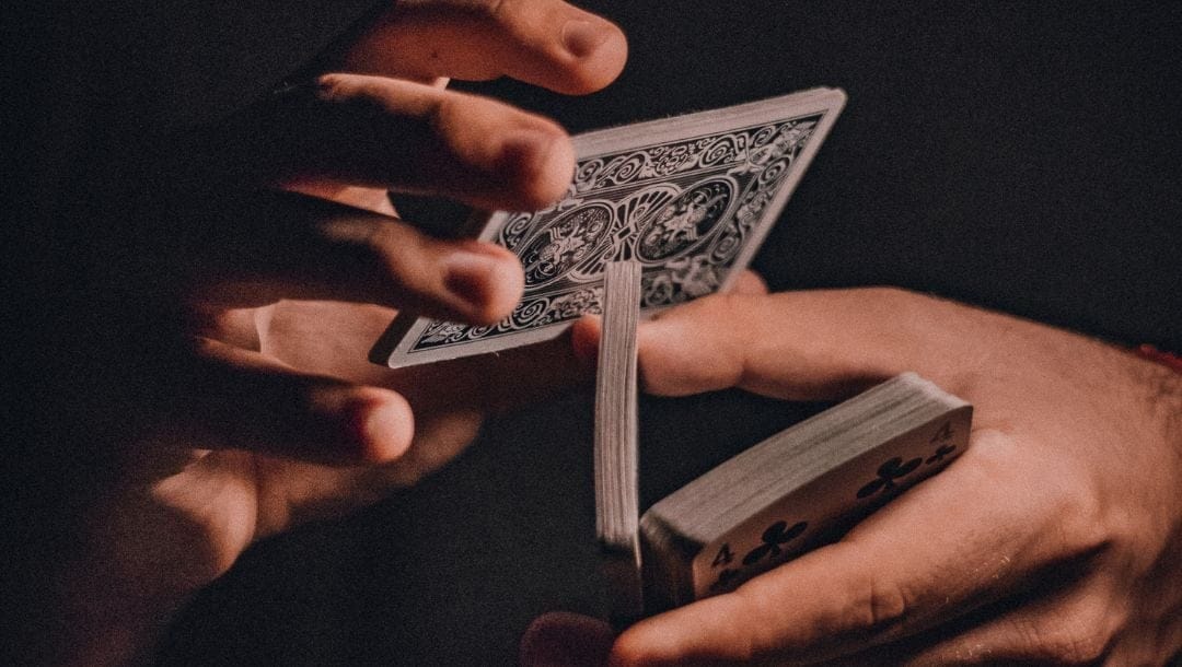 A close-up shot of a man’s hands shuffling cards.