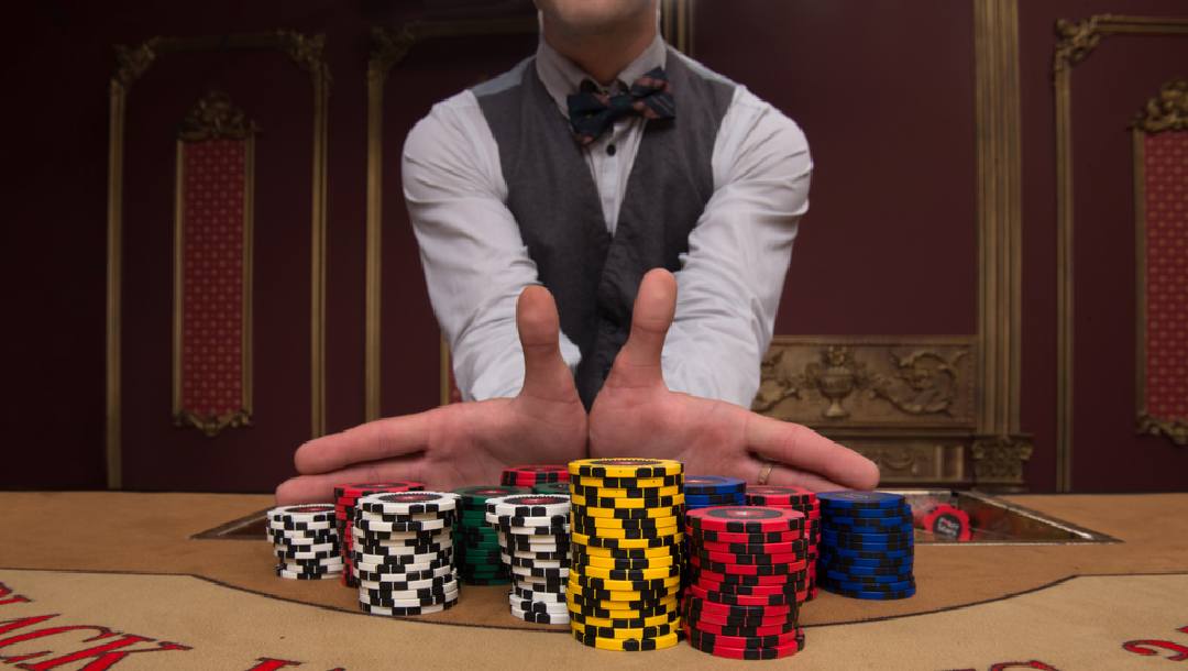 A casino dealer pushing chips onto the table.