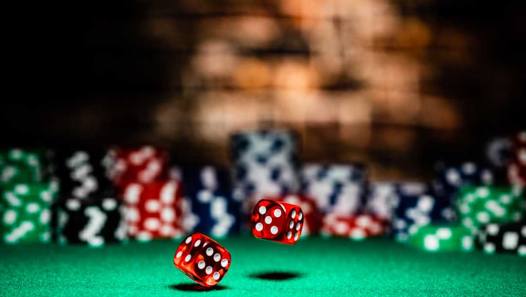 Two dice rolling on a casino table, with one in mid-air.