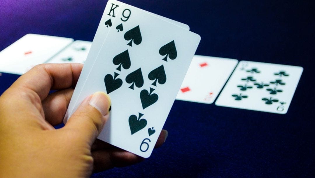 A hand with a king and nine card with some cards in the background