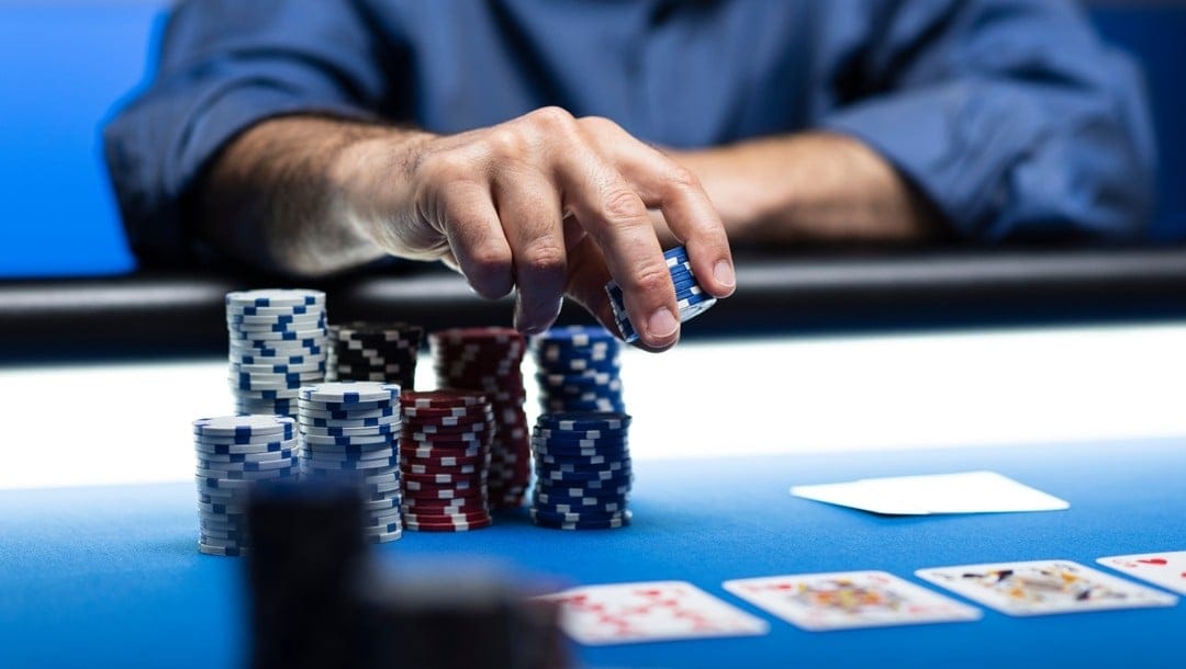 Player betting chips at casino, with poker cards on the table