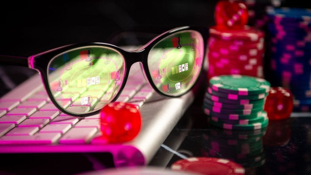 A pair of AR glasses on a keyboard next to some casino chips with a poker game in the lenses.