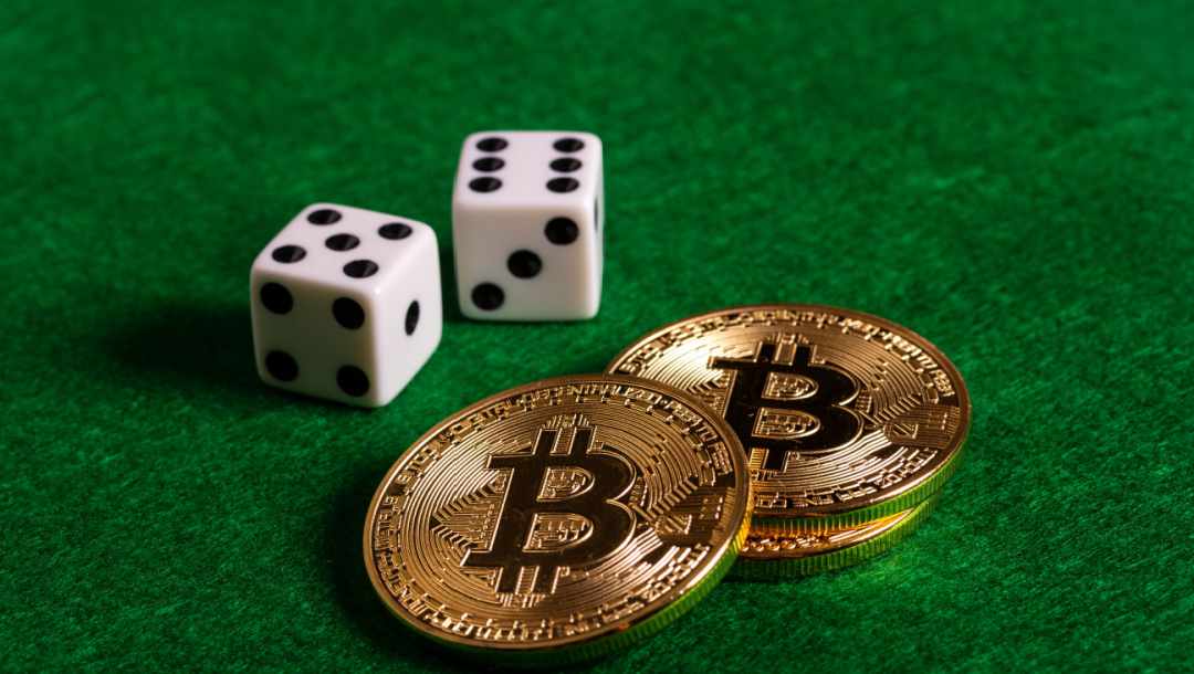 Two crypto coins next to dice on a poker table