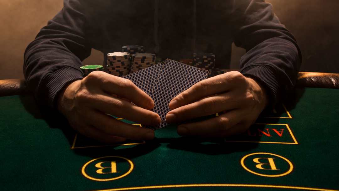 A player holding cards with stacks of chips in front of them.