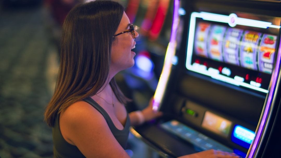 A person sitting at a slot machine, inside a casino.