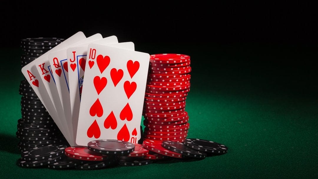 A royal flush leaning against stacks of red and black poker chips.