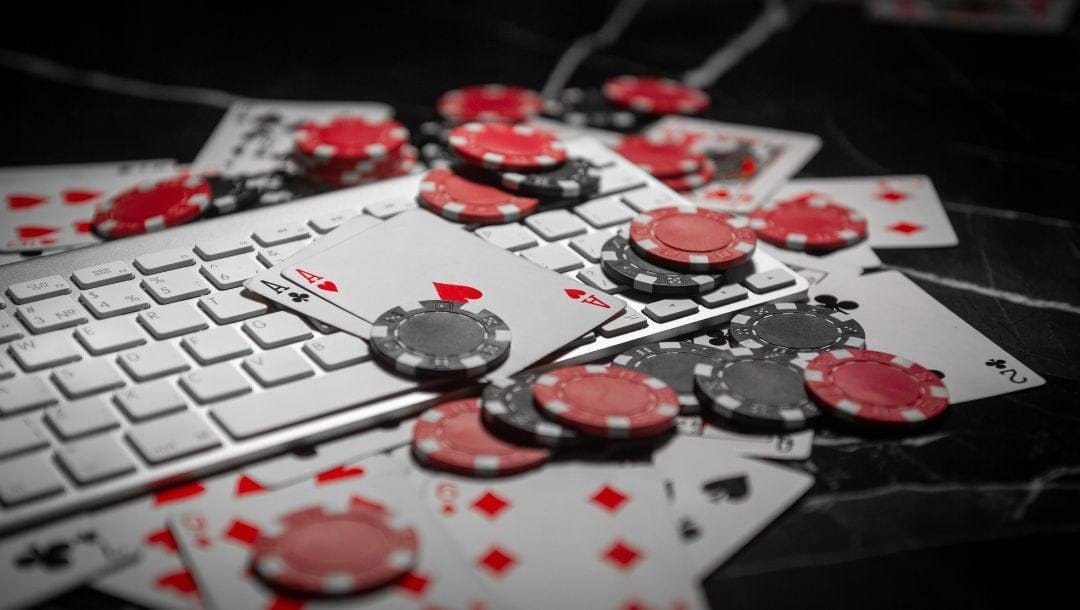 A white keyboard with playing cards and poker chips scattered around.