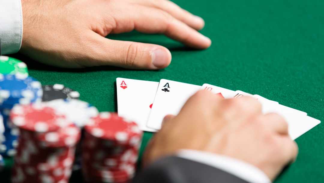 A poker player lays their cards on the table next to a stack of chips