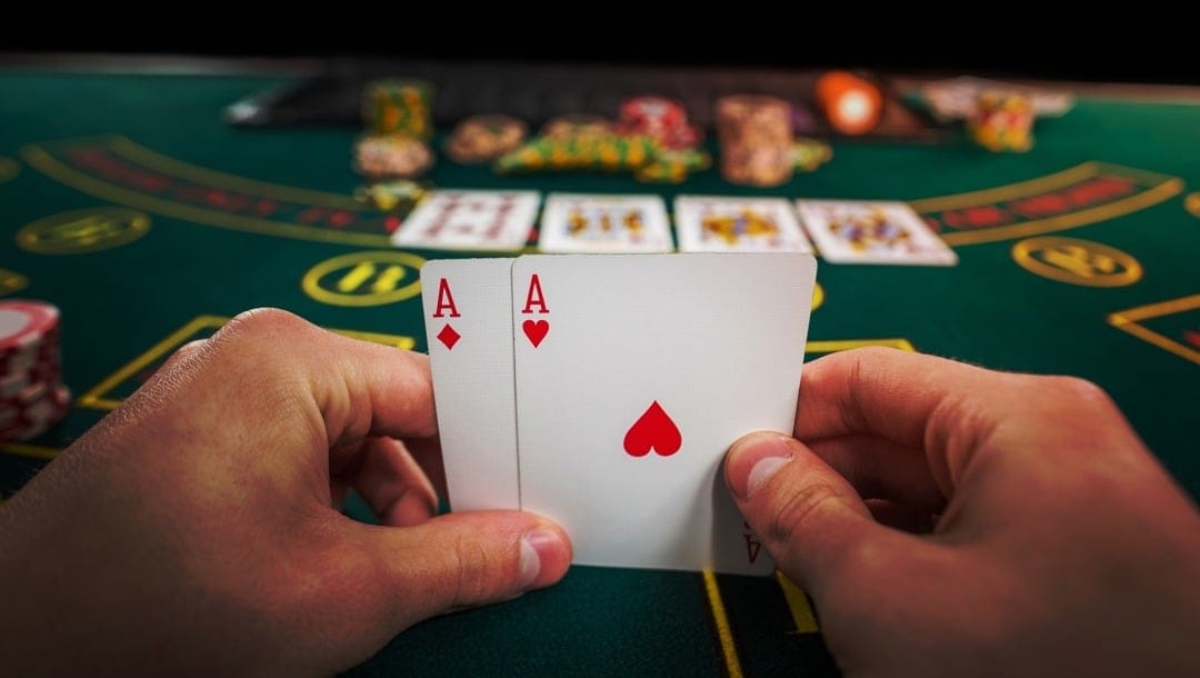 Poker player holding two aces at a green casino table