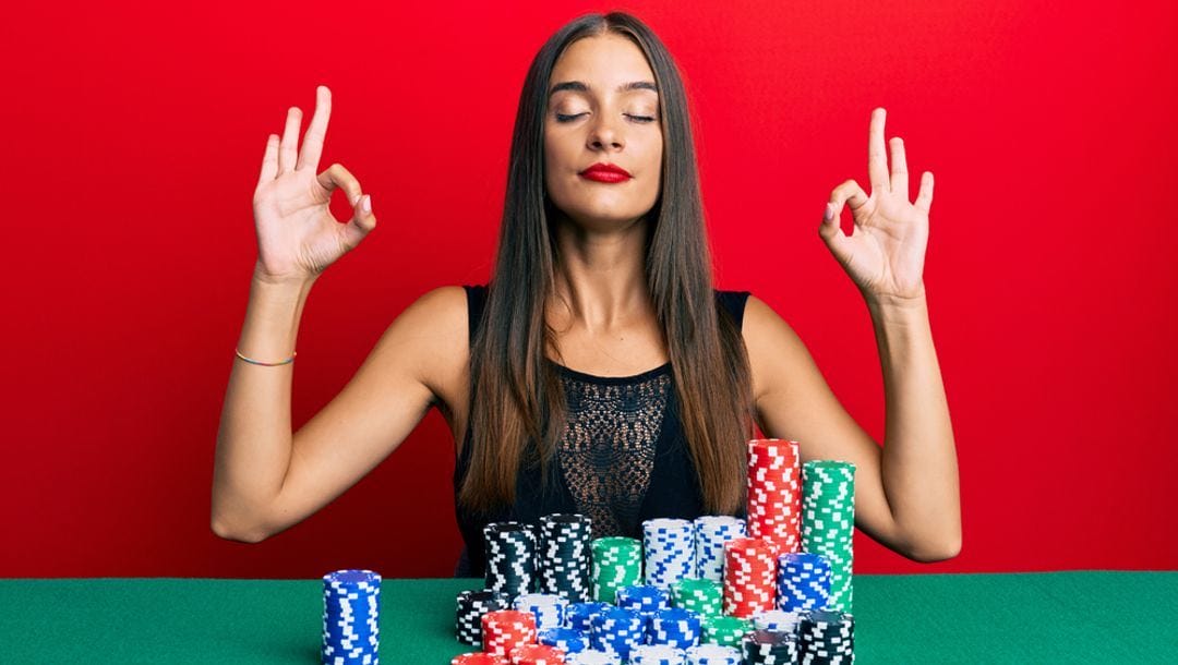 A person meditating in front of stacks of poker chips.