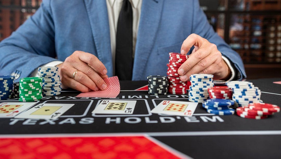 A poker player in a blue suit checking their hole cards while deciding what to bet.