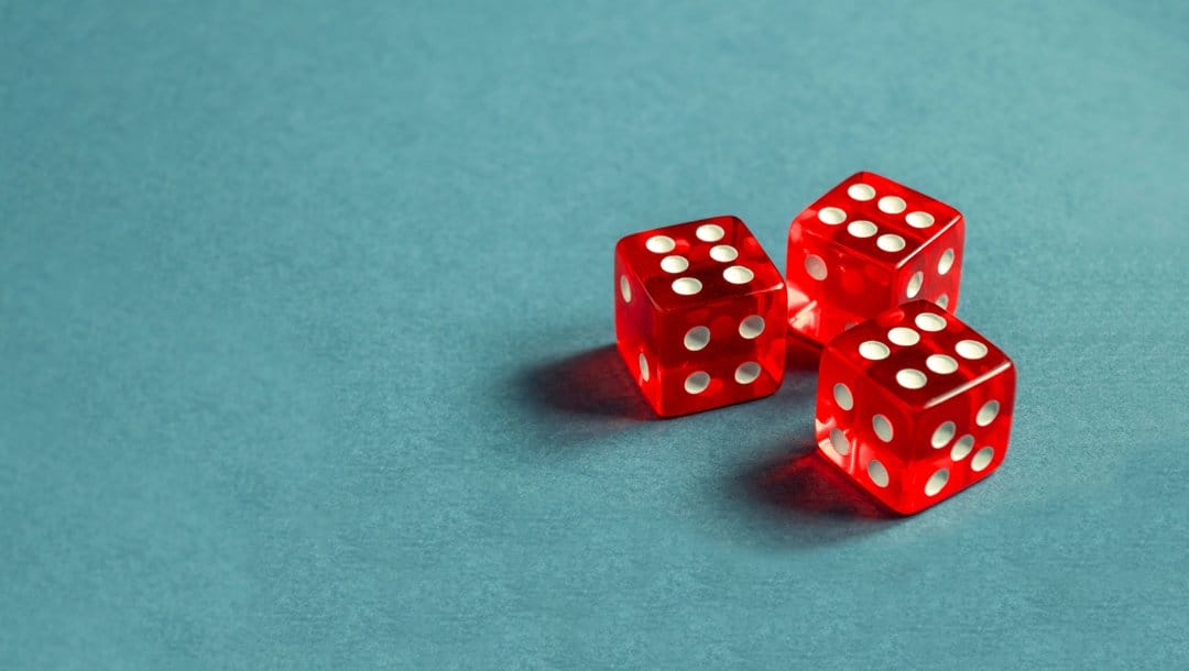 Three red dice on a blue table.