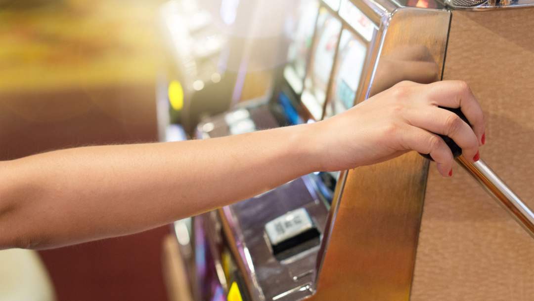 A person pulling the spin mechanism on a slot machine.