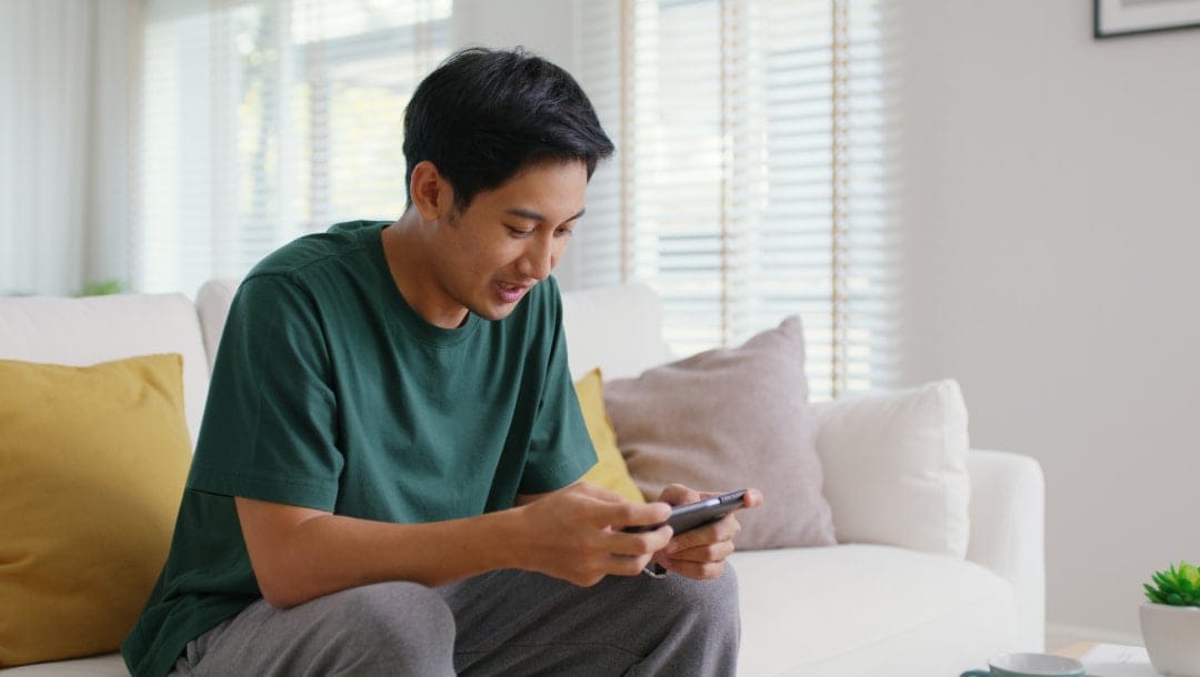 A man sitting on the couch looking at his smartphone.