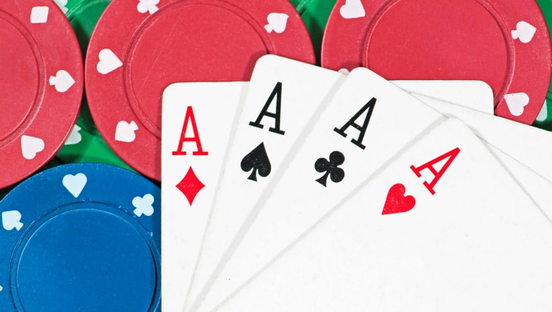 Four aces spread out over a background of layered casino chips.