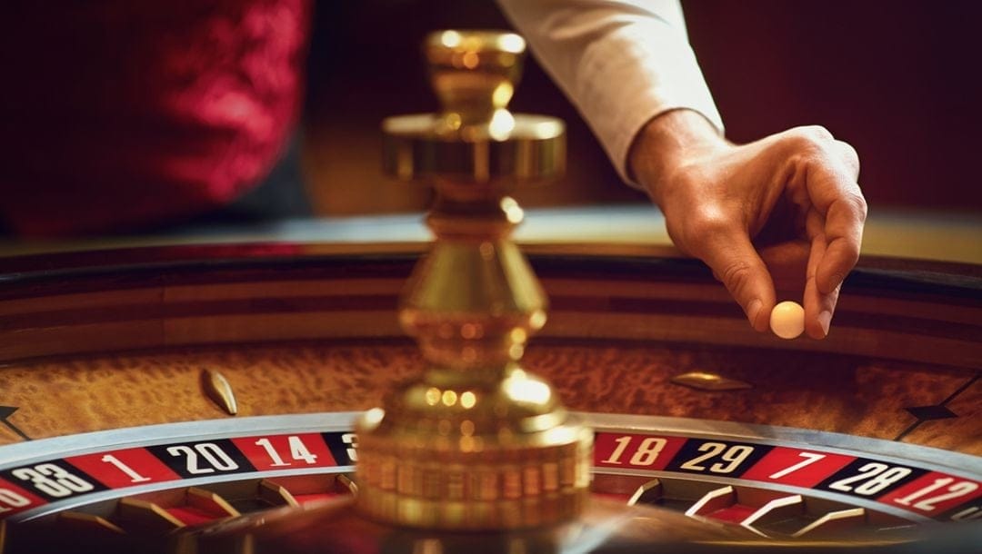 A croupier placing the ball on a roulette wheel.