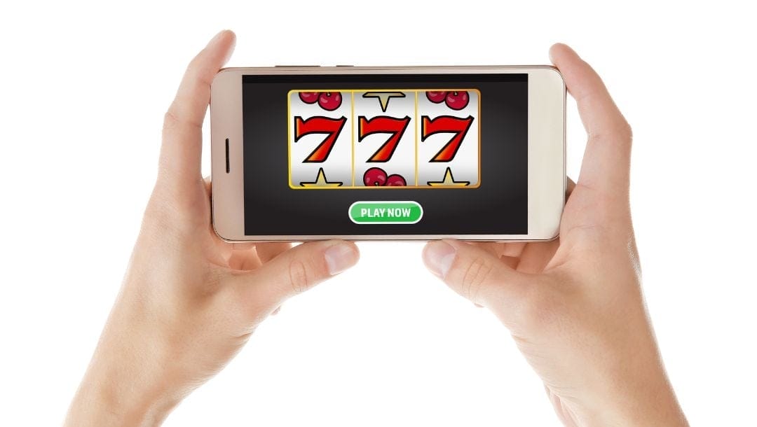 A person holding a cellphone, playing an online slot game.