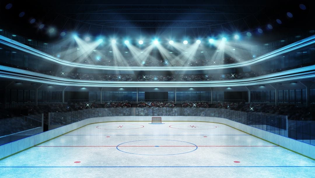A wide shot of an ice hockey stadium with spectators as bright lights shine down on the rink.