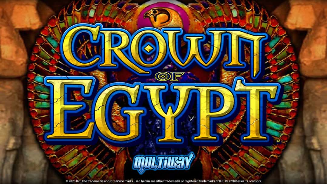 Crown of Egypt online slot logo in yellow and blue. The logo is placed on a mosaic wing of a bird. There are brown rocks in the background.