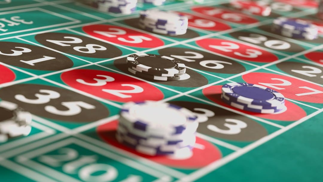 An extreme closeup of various bets placed on different numbers on a casino roulette table.