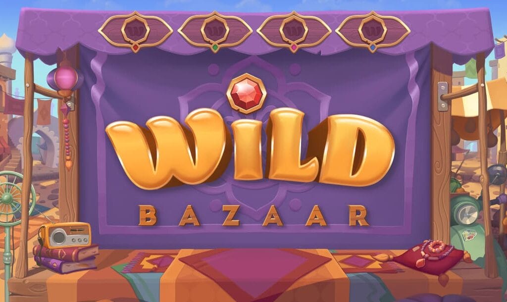 Wild Bazaar online slot game logo in gold. The logo is against a purple backdrop. There is a cushion, books, a radio, a motorcycle, and a fan below the logo.