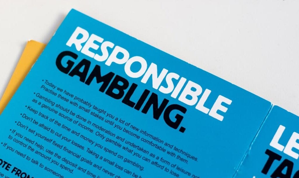 A photograph of a blue pamphlet on a white table. The pamphlet has the words “Responsible Gambling” written in bold, capital letters at the top as well as a few summary points and tips for responsible gamling below it.