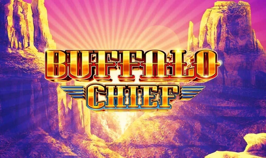 The title screen of the Buffalo Chief slot game. The game title is written in gold, capital letters with blue and red outlines. In the background is a desert mountain scene with the sun rising between the mountains.