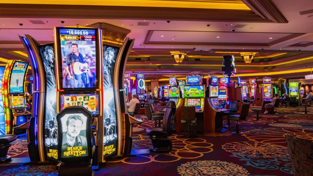 The interior of a casino. There are dozens of slot machines on the casino floor.