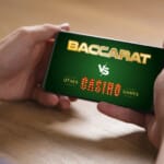 A person holding a smartphone displaying a green screen with the text “Baccarat vs Other Casino Games” in bold, stylized fonts.