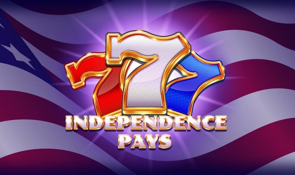 The Independence Pays slot banner. The background is a close-up of an American flag as it waves in the wind. In the foreground is the game logo. It features a red, white, and blue seven with a gold border. The game title is below the three sevens and is captured in a white font with a gold border.